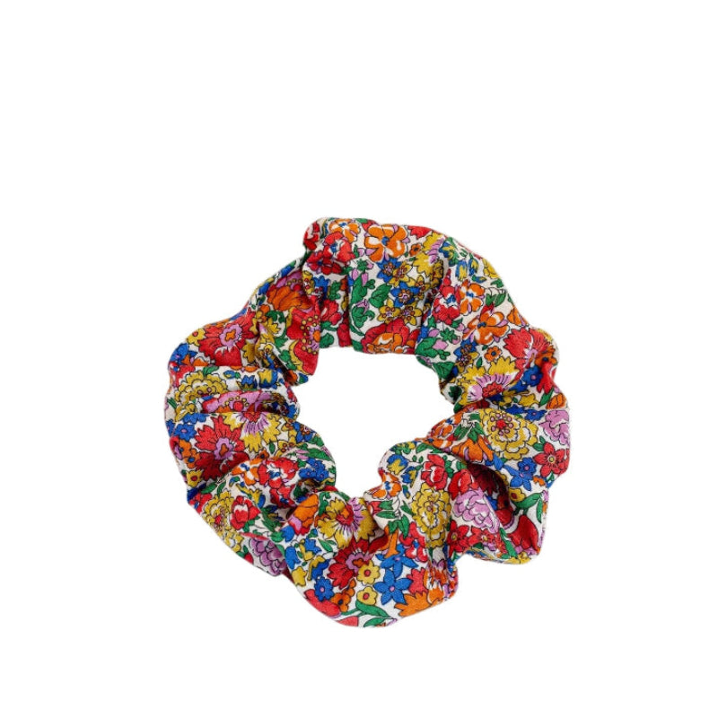 Liberty of London | Nell, Annie and May C Red Fabric Print Scrunchie.&nbsp; Add a touch of timeless elegance to your hairstyle with this iconic Liberty of London Tana Lawn cotton print scrunchie. Featuring outlined meadow flowers like roses, bluebells, and daisies, this quintessential botanical fabric mimics 19th-century woodblock impressions.