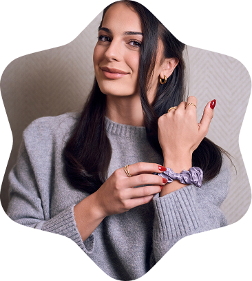Woman wearing a gray sweater holding a purple scrunchie.